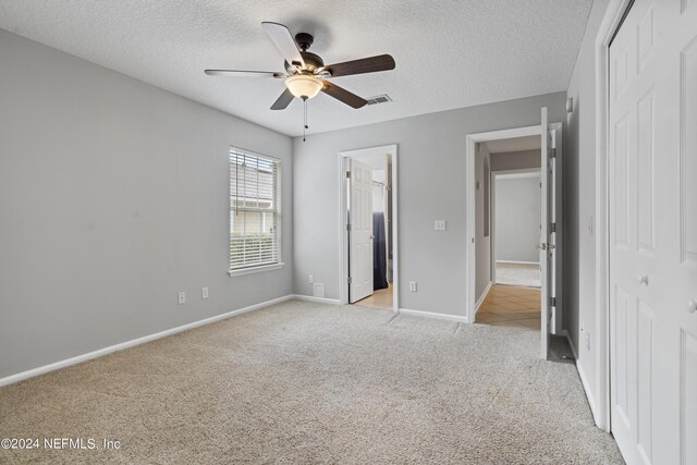 unfurnished bedroom featuring ceiling fan, light colored carpet, and a closet