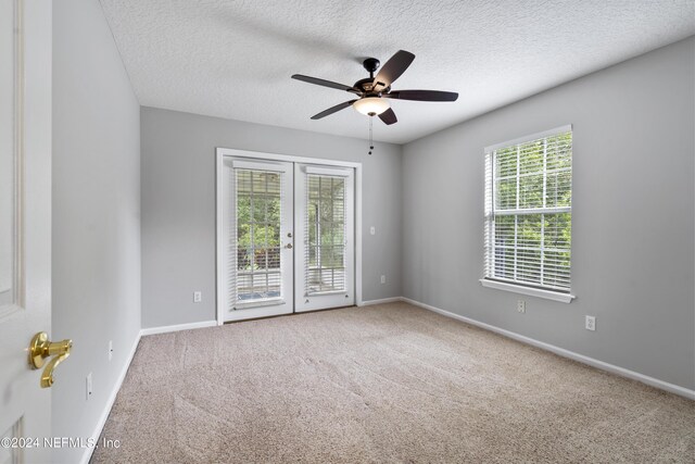 spare room with ceiling fan, carpet floors, french doors, and a wealth of natural light