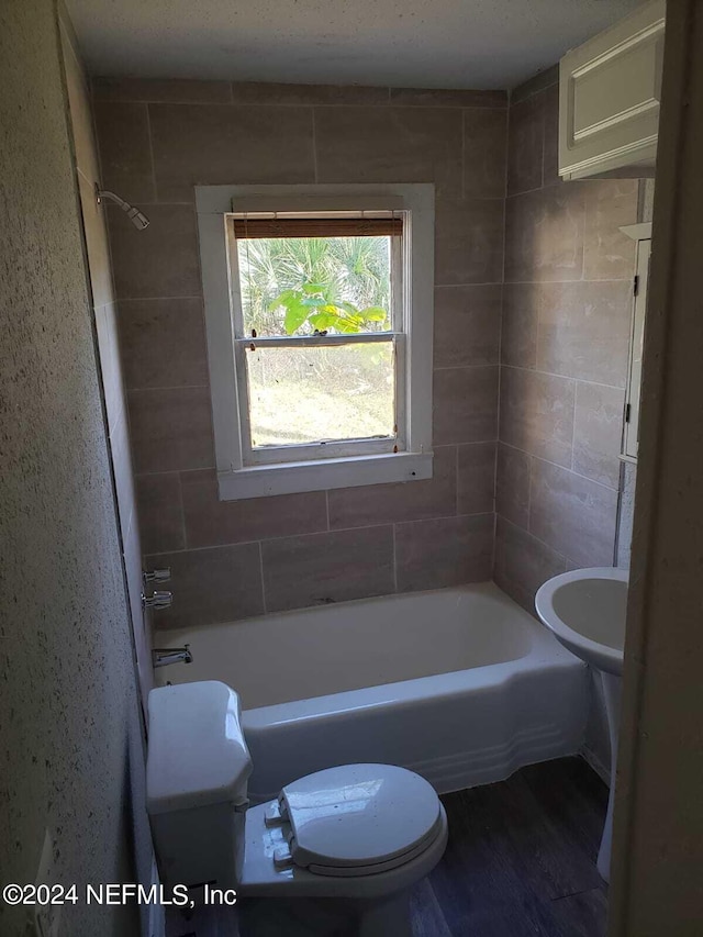 bathroom featuring tiled shower / bath combo, toilet, and wood-type flooring