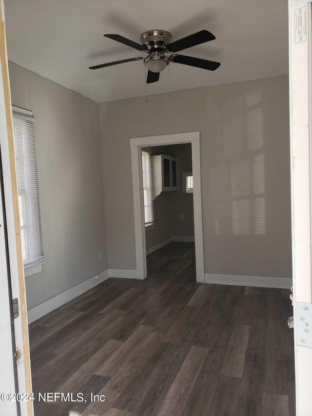 empty room with ceiling fan and dark hardwood / wood-style flooring