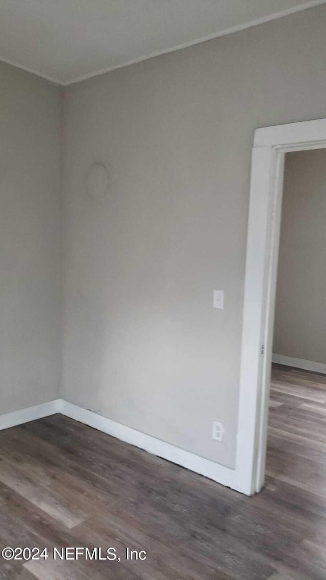 spare room featuring ornamental molding and dark wood-type flooring