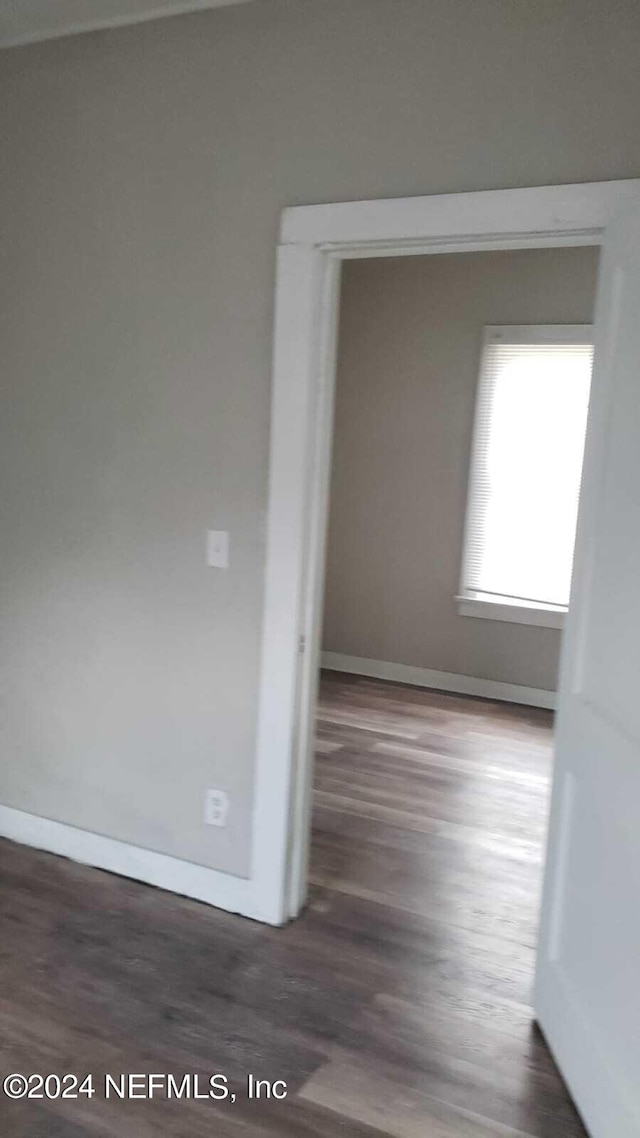 unfurnished room with dark wood-type flooring