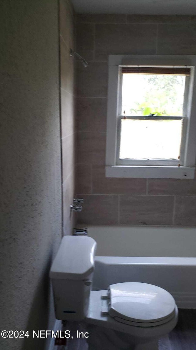 bathroom featuring tiled shower / bath combo and toilet