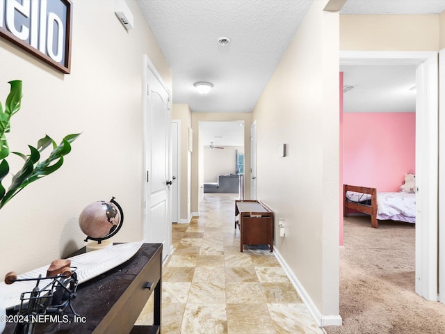 hallway with a textured ceiling and light colored carpet