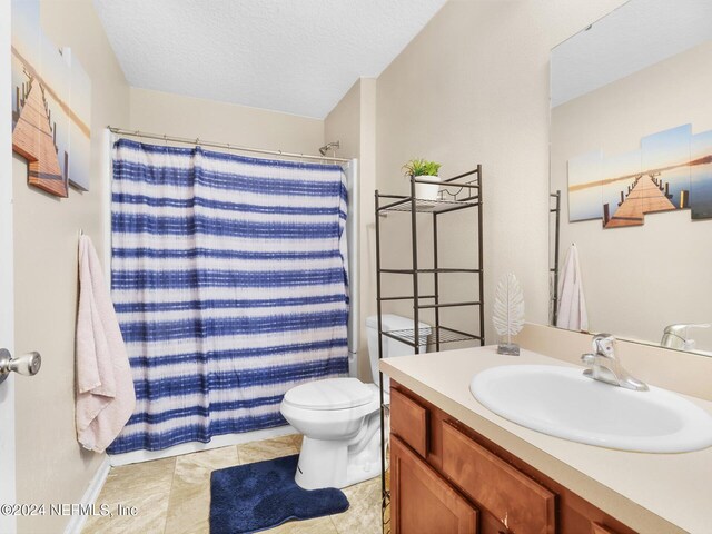 bathroom with vanity, curtained shower, a textured ceiling, and toilet