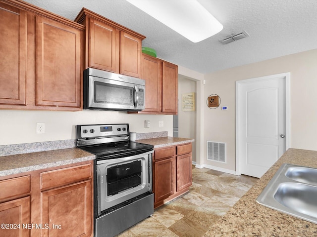 kitchen featuring sink, appliances with stainless steel finishes, and a textured ceiling