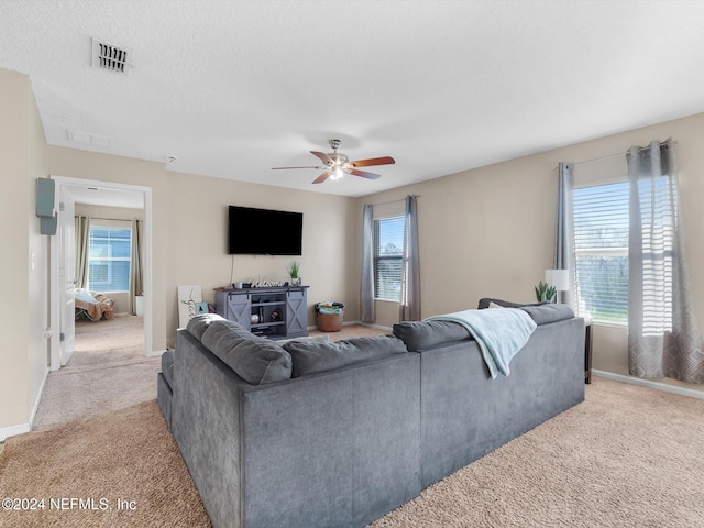 carpeted living room with a textured ceiling and ceiling fan