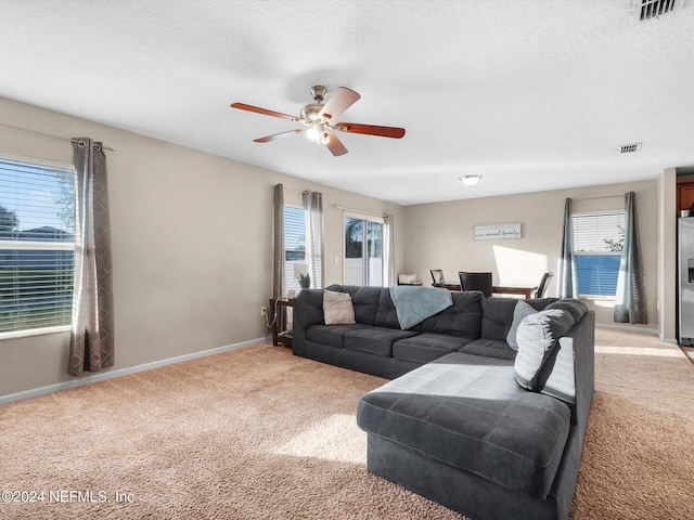 carpeted living room featuring ceiling fan and a textured ceiling