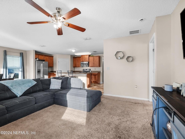 carpeted living room with a textured ceiling and ceiling fan