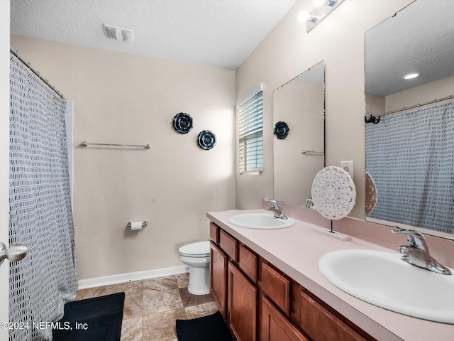 bathroom with toilet, a textured ceiling, walk in shower, and vanity