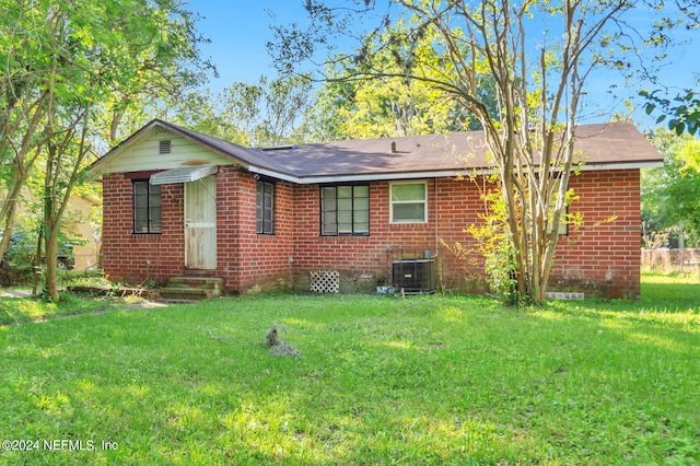 view of front of house with a front lawn and central AC