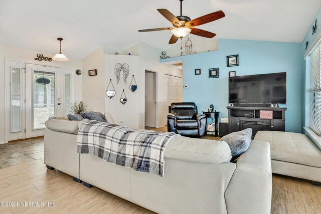 living room with ceiling fan, light hardwood / wood-style floors, and vaulted ceiling