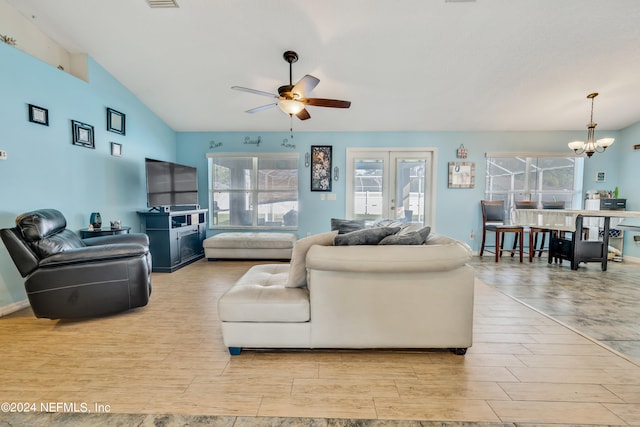 living room featuring ceiling fan with notable chandelier, plenty of natural light, lofted ceiling, and light hardwood / wood-style flooring