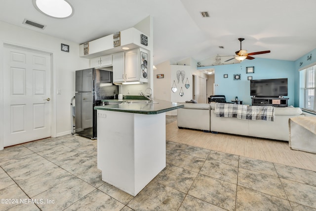 kitchen with white cabinets, kitchen peninsula, lofted ceiling, ceiling fan, and black fridge