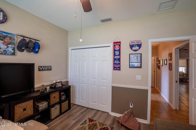 interior space with ceiling fan, a textured ceiling, a closet, and wood-type flooring