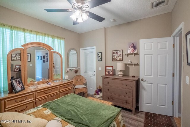 bedroom with ceiling fan, a textured ceiling, and light hardwood / wood-style floors