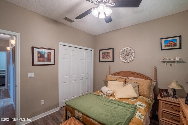 bedroom featuring a closet, ceiling fan, a textured ceiling, and dark hardwood / wood-style flooring