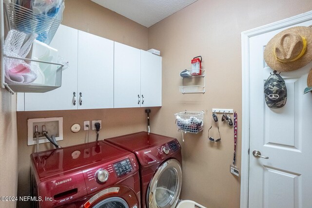 washroom featuring cabinets, a textured ceiling, and washer and dryer