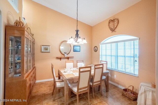 tiled dining space featuring an inviting chandelier and lofted ceiling