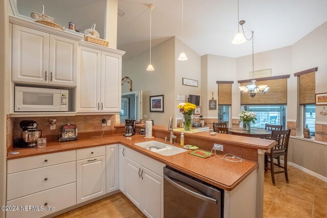 kitchen with kitchen peninsula, white microwave, dishwasher, decorative light fixtures, and sink