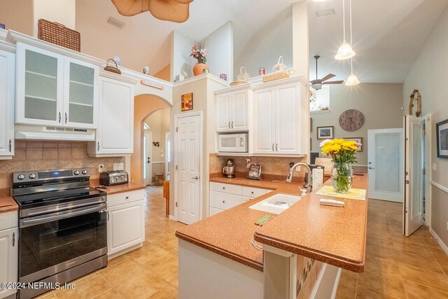 kitchen with ceiling fan, decorative light fixtures, high vaulted ceiling, stainless steel range with electric cooktop, and white microwave