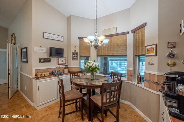 tiled dining area with a notable chandelier and high vaulted ceiling