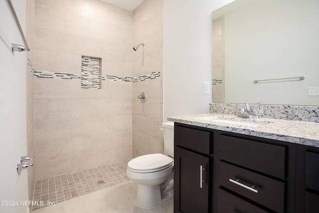 bathroom featuring tiled shower, vanity, toilet, and tile patterned flooring