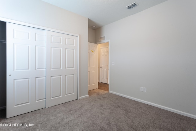 unfurnished bedroom featuring light carpet and a closet