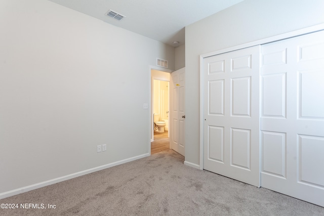 unfurnished bedroom featuring a closet and light colored carpet