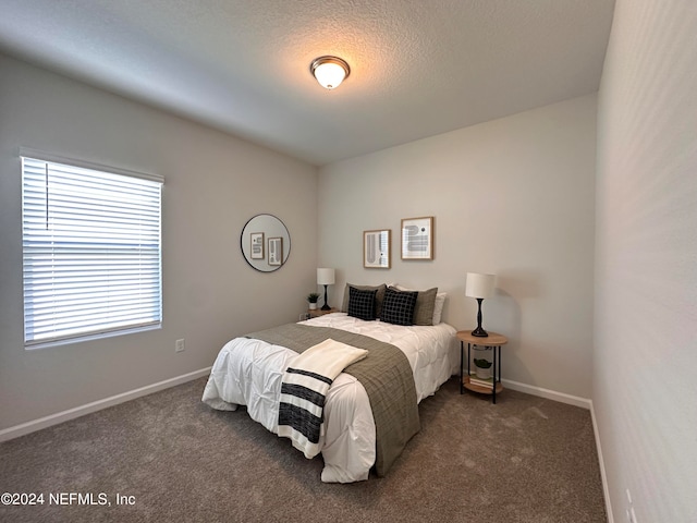 bedroom with a textured ceiling and dark colored carpet