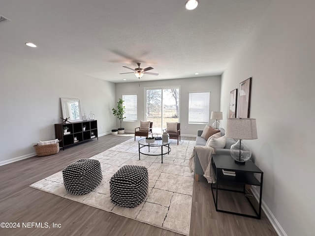 living room with ceiling fan, a textured ceiling, and light hardwood / wood-style floors