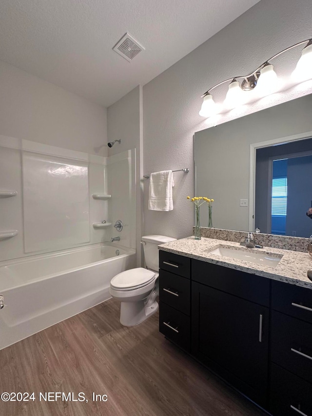 full bathroom featuring shower / washtub combination, vanity, a textured ceiling, toilet, and hardwood / wood-style floors