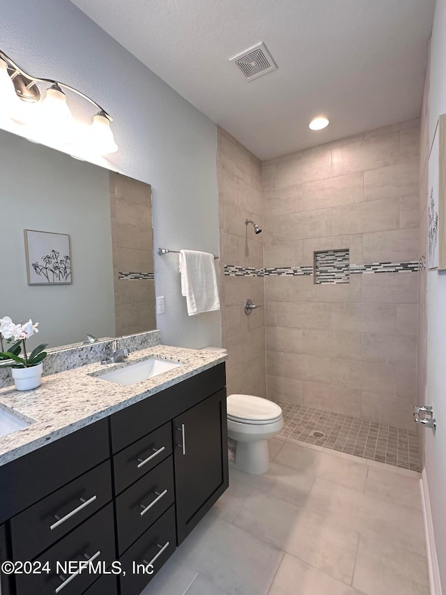 bathroom featuring vanity, toilet, and tiled shower