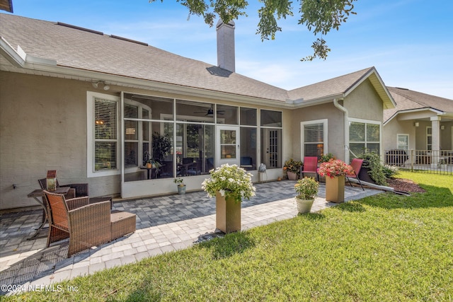 rear view of property with a lawn, a sunroom, and a patio area