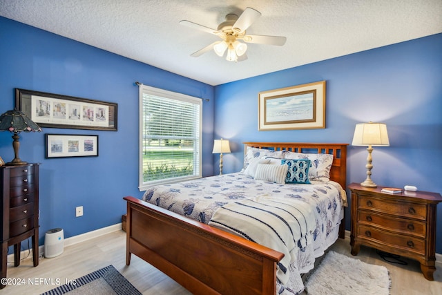 bedroom with light hardwood / wood-style floors, ceiling fan, and a textured ceiling