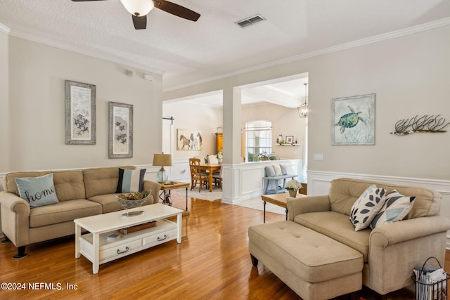 living room with ornamental molding, wood-type flooring, ceiling fan, and a textured ceiling