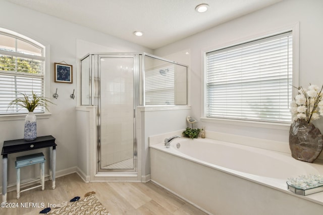 bathroom featuring wood-type flooring, separate shower and tub, and plenty of natural light