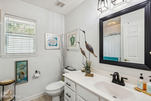 bathroom with a textured ceiling, wood-type flooring, vanity, and toilet