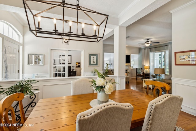 dining room featuring ornamental molding, a textured ceiling, ceiling fan with notable chandelier, and hardwood / wood-style floors