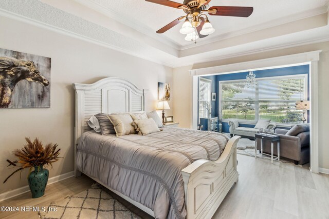 bedroom with ceiling fan, light hardwood / wood-style flooring, crown molding, and a raised ceiling