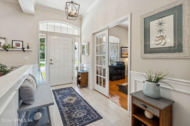 entryway with an inviting chandelier, light hardwood / wood-style flooring, and ornamental molding