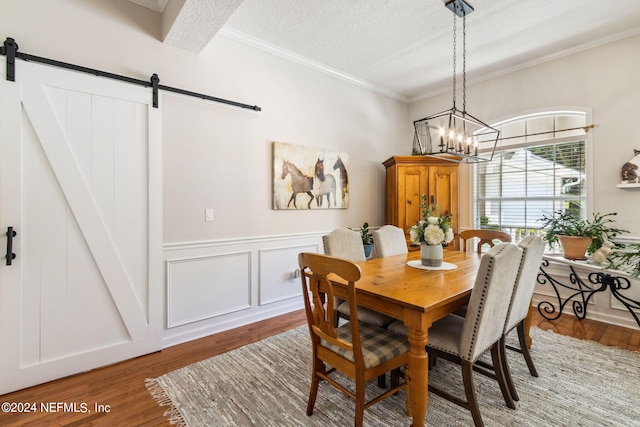 dining area featuring wood-type flooring, a textured ceiling, a chandelier, and a barn door