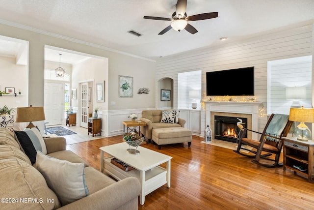 living room with crown molding, ceiling fan, and light hardwood / wood-style flooring