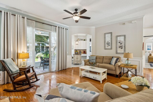 living room featuring a textured ceiling, crown molding, ceiling fan, and light hardwood / wood-style flooring