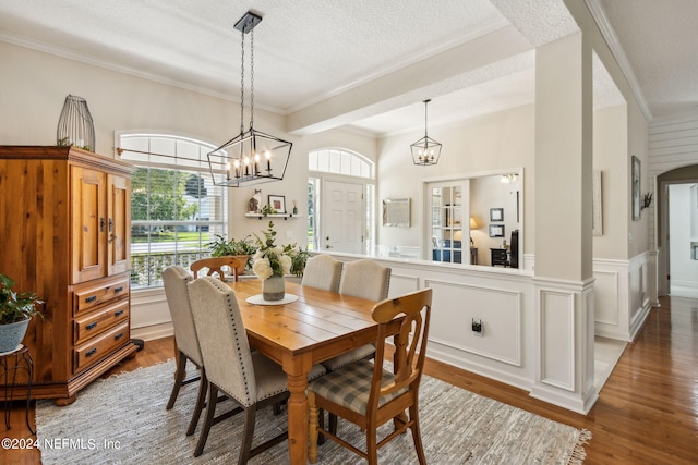 dining area with a textured ceiling, ornamental molding, a chandelier, and hardwood / wood-style flooring