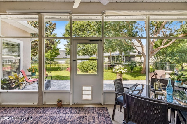 sunroom / solarium featuring ceiling fan and beamed ceiling