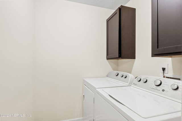 laundry area with independent washer and dryer, cabinets, and a textured ceiling