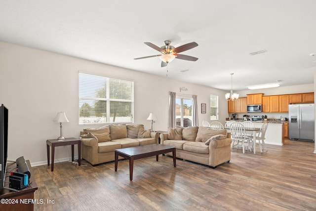 living room featuring dark hardwood / wood-style flooring and ceiling fan with notable chandelier