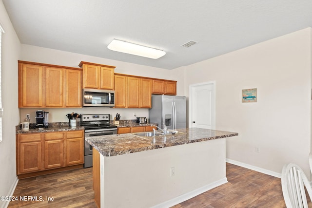 kitchen featuring stainless steel appliances, a kitchen island with sink, sink, and dark hardwood / wood-style floors