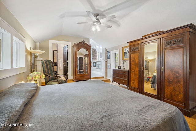 bedroom with light wood-type flooring, ensuite bathroom, vaulted ceiling, and ceiling fan